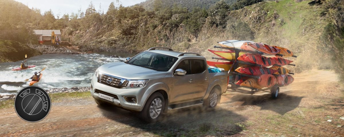 Nissan Navara towing canoes in the mountain close to a lake with 4 wheel drive high illustration